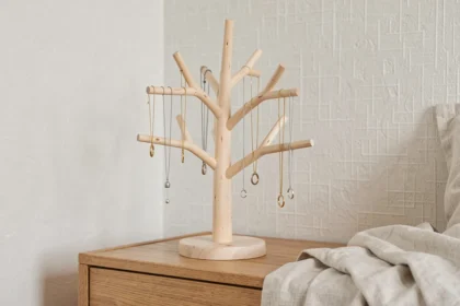 Arbre à bijoux en bois minimaliste posé sur une commode en chêne clair avec colliers et boucles d'oreilles suspendus, style scandinave épuré