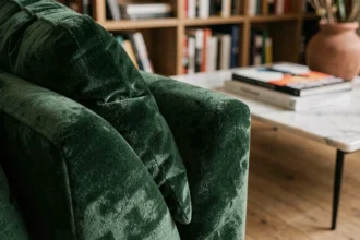 Gros plan sur un canapé en velours vert forêt dans un salon contemporain parisien avec parquet en chêne