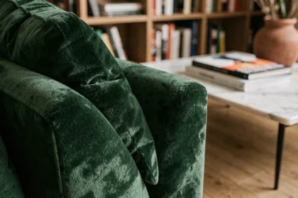 Gros plan sur un canapé en velours vert forêt dans un salon contemporain parisien avec parquet en chêne