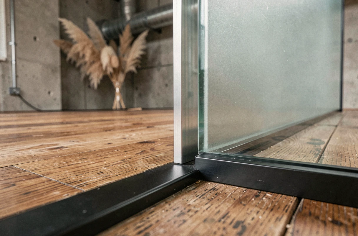 Détail d'assemblage d'une cloison en verre dépoli sur parquet chêne dans un loft industriel rénové