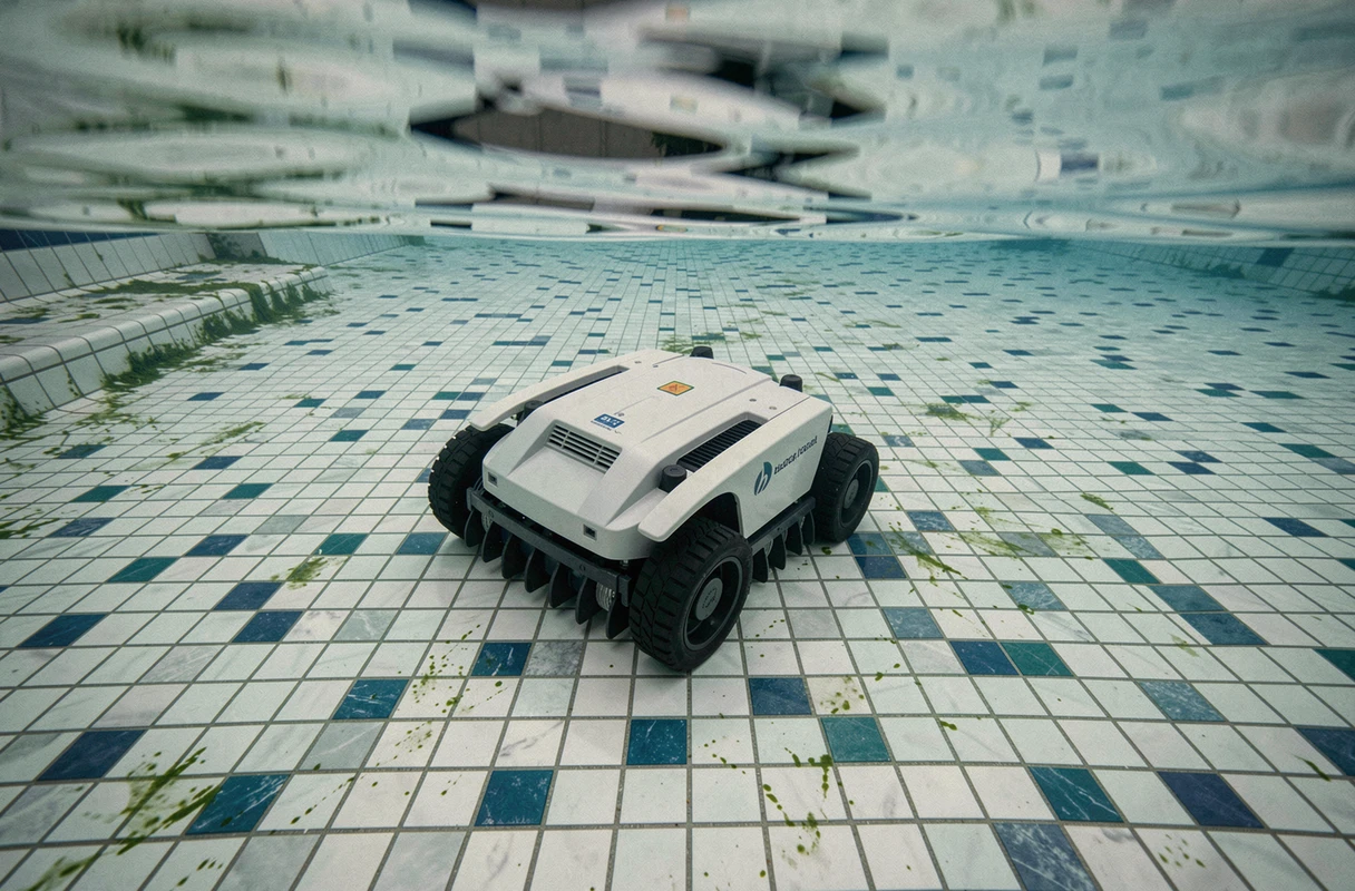 Robot nettoyeur de piscine autonome éliminant les dépôts d'algues sur le fond carrelé d'une piscine privée