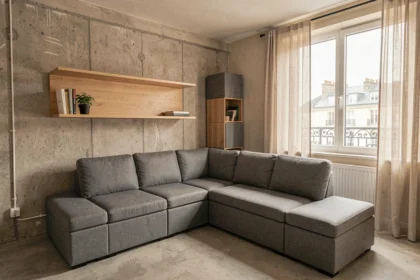 Salon de petit appartement avec canapé modulable gris et bureau mural rabattable en bois clair